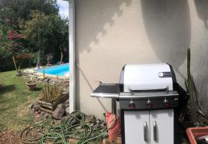 einem Grill neben einem Haus mit Pool in der Unterkunft Villa Sybelle- piscine - 3min plage in Le Diamant