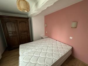 una camera con un letto bianco su una parete rosa di Chez Alice - Isigny le Buat a Isigny-le-Buat