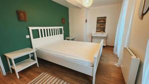 una camera con un letto bianco e una parete verde di Chez Alice - Isigny le Buat a Isigny-le-Buat