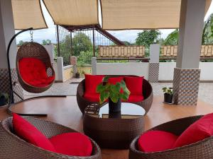 un patio con sillas y una mesa con almohadas rojas en Apartelle near Philippine Arena en Bulakan