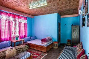 een woonkamer met blauwe muren en roze gordijnen bij 3 Sisters' Homestay in Ravangla