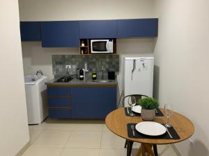 a kitchen with blue cabinets and a table and a refrigerator at Studio Standard Comfort I AO LADO SHOPPING in Três Lagoas