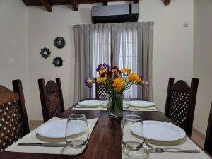 una mesa con platos y un jarrón de flores. en Casa confortable en Luján de Cuyo, Mendoza. en Luján de Cuyo