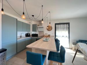 a kitchen with a large wooden table and blue chairs at BEL'ORIZONTE C, 100m des plages et vue mer in Propriano +16 photos