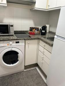 a kitchen with a washing machine and a microwave at Apartamento Fibes-Congresos Parking Gratis in Seville