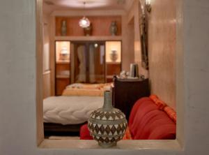 Habitación con cama y jarrón en un estante en Riad Tama & spa, en Ouarzazate