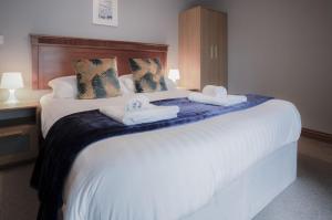 um quarto com uma cama grande e toalhas em Rose Coach House - 3 Bedroom Cottage - Pendine em Pendine