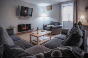 uma sala de estar com um sofá e uma mesa em Rose Coach House - 3 Bedroom Cottage - Pendine em Pendine