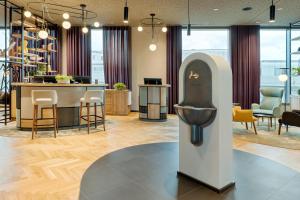 a hotel lobby with a bar with chairs and tables at BASSENA Wien Donaustadt in Vienna