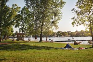 a person laying on a blanket in a park next to a lake at BASSENA Wien Donaustadt in Vienna