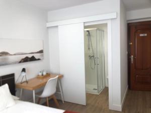 a bedroom with a bed and a desk and a shower at Pensión Amara in San Sebastián