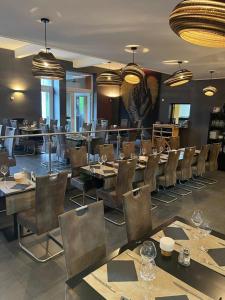 un comedor con mesas y sillas en un restaurante en Hotel Le Midi, en Petit-Rechain