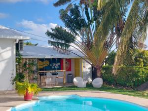 a swimming pool in front of a building with a palm tree at Villa BELLE VUE, CHAMBRE BAMBOUS in Ravine des Cabris