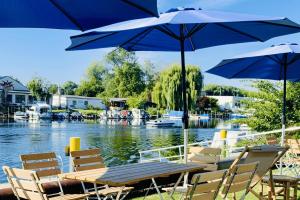 einen Tisch und Stühle mit Sonnenschirmen neben einem Fluss in der Unterkunft havelblau Ferienlofts in Brandenburg an der Havel