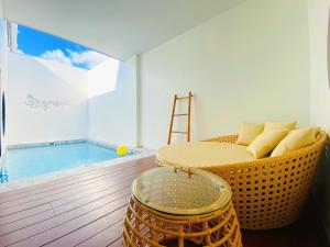 a living room with a wicker chair next to a pool at Chul Boutique Villa จุล บูทิค วิลล่า in Ban Ba Ngan