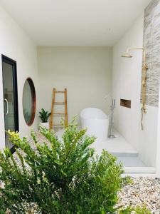 ein Badezimmer mit einer Badewanne und einer Pflanze in der Unterkunft Chul Boutique Villa จุล บูทิค วิลล่า in Ban Ba Ngan