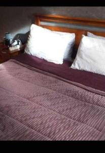 a bed with a purple blanket and white pillows at location nuit pour les familles in Settat