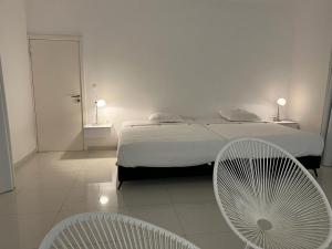 a bedroom with a bed and two white chairs at Villa Carabane in Somone