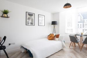 Dormitorio blanco con cama y mesa en Connaught House - City Centre - Free Parking & Wi-Fi, en Cardiff