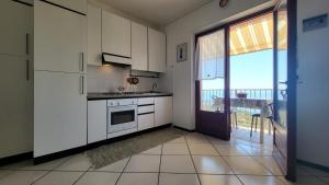 a kitchen with white cabinets and a door to a balcony at Appartamento Bellavista in Capoliveri