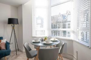 a dining room with a table and chairs and windows at Connaught House - City Centre - Free Parking & Wi-Fi in Cardiff
