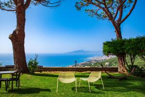 dwa krzesła i stół w parku z widokiem na ocean w obiekcie Olivenere agriturismo w mieście Lavagna