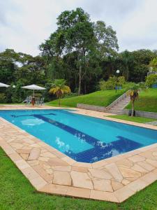 a swimming pool in the grass next to a park at CHÁCARA STA EDWIGES/ARUJA in Arujá