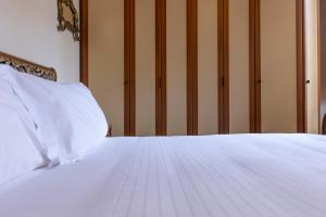 białe łóżko z białą pościelą i poduszkami w obiekcie Fossi Elegant Apartment we Florencji
