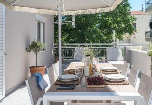 una mesa en un patio con sombrilla en Sofias LemonTree Family House en Ágios Nikólaos