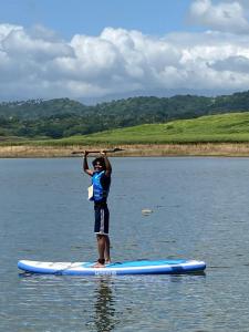 a man standing on a paddle board in the water at Randeniya Hena in Teldeniya