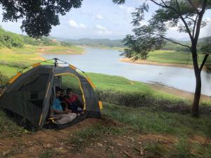 two men sitting in a tent next to a river at Randeniya Hena - Kandy in Teldeniya
