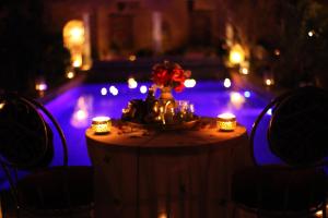 Una mesa con velas y un jarrón con flores. en Riad Tama & spa en Ouarzazate