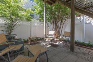 a patio with wooden tables and chairs and trees at Sunny convenient home w/ private patio! Easy walk to everything! in Boston