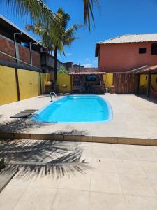 een zwembad in een tuin met een huis bij POUSADA FLOR DO CARIBE in Rio das Ostras