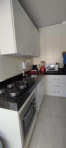 a kitchen with white cabinets and a stove top oven at Casa Praia Dunas do Peró in Cabo Frio