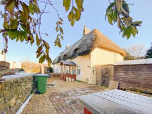 a thatch roofed house with a picnic table in front of it at The Farm Cottage in Bognor Regis