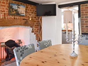 a dining room with a table and a fireplace at The Farm Cottage in Bognor Regis