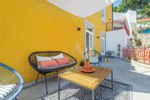 een patio met een tafel en stoelen en een gele muur bij Monte dos Judeus I by Innkeeper in Porto