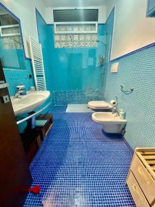 a blue tiled bathroom with a toilet and a sink at HomeClass in Bari