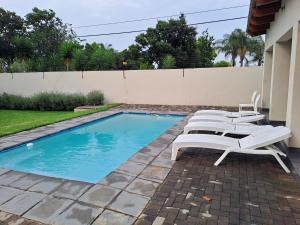 a swimming pool with lounge chairs next to a house at Cozy Sparrow Hideaway in Sandton