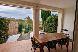 een houten tafel en stoelen op een patio bij Les Restanques Maison 14 Chênes in Grimaud