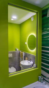 a green bathroom with a sink and a mirror at Babvirág Porta Fonyódliget in Fonyód