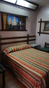 1 dormitorio con 1 cama con una manta colorida en Hotel Iberia en Córdoba