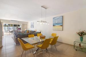 a living room with a dining table and yellow chairs at Villa Nicola in Vale do Lobo