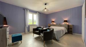 Saint-Jean-le-VieuxにあるMaison Zubiatia - 3km Compostelleの紫の壁のベッドルーム1室、ベッド1台、椅子2脚が備わります。