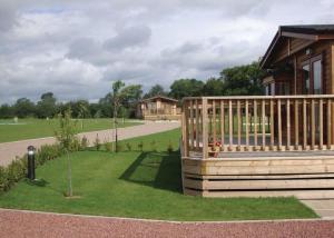 a wooden house with a deck and a yard at York House Country Park in Thirsk
