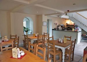 a restaurant with wooden tables and chairs and a kitchen at York House Country Park in Thirsk