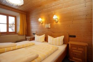 two beds in a room with wooden walls at Obersteinberg-Hof in Ruhpolding