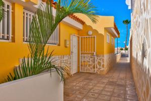 a yellow house with a gate and a palm tree at Las Brisas FREE WIFI in Adeje