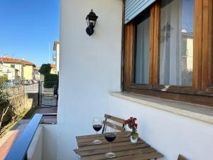 two glasses of wine sitting on a bench on a balcony at Appartamento VN House in Pisa